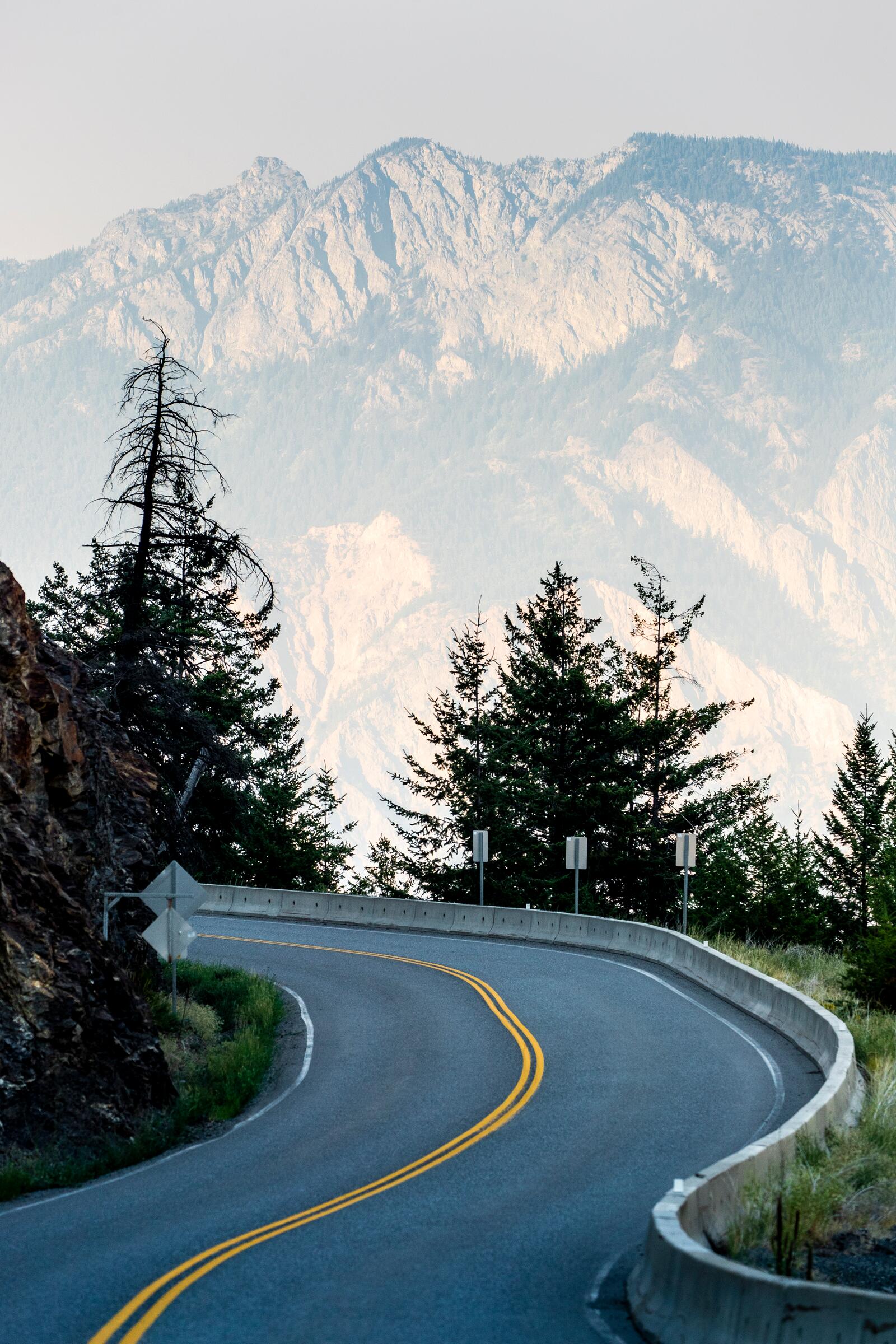 Empty two-lane highway curving through the Nass Valley toward a mountain wall